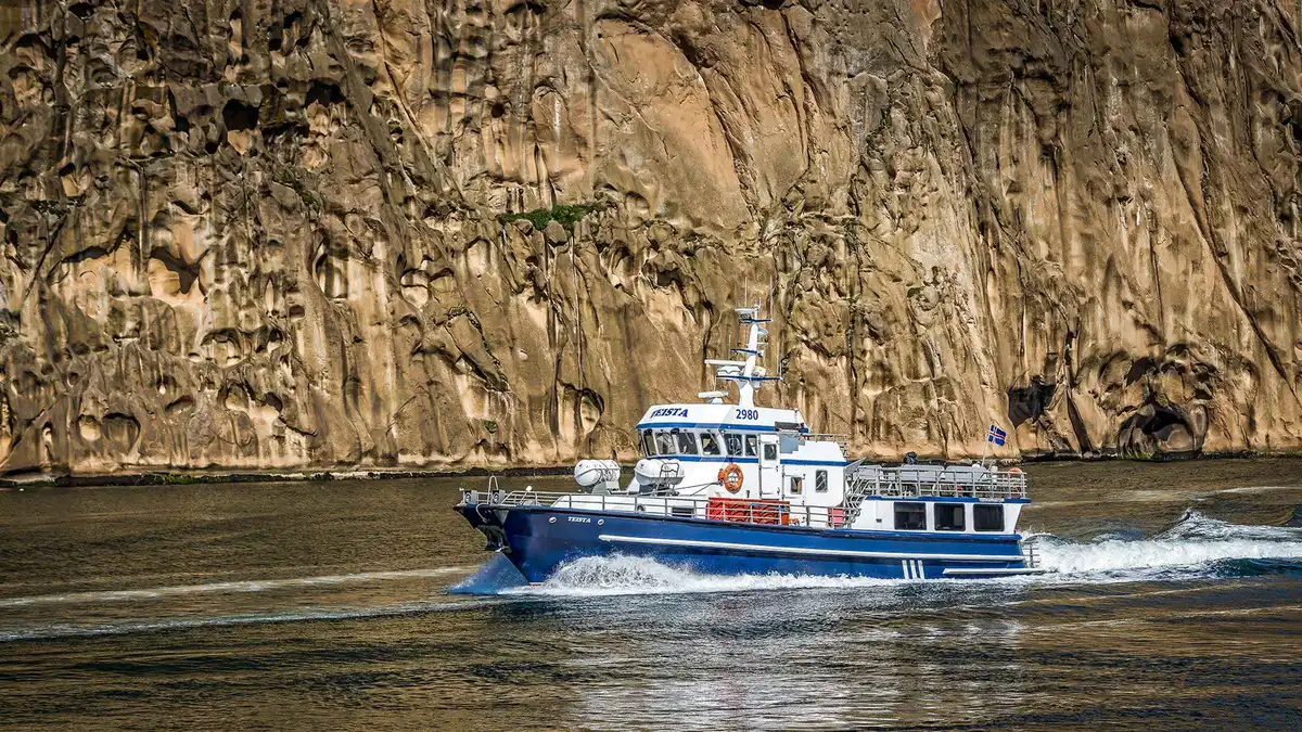 Boat below the Eldfell lava cliffs at Heimaey on a Westman Islands Iceland volcano tour