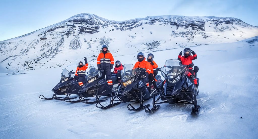Group of snowmobilers in bright gear on a snowy glacier — Snowmobiling on Eyjafjallajökull