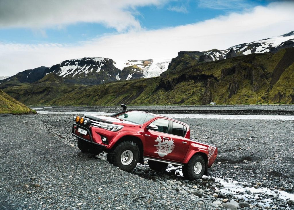 Red Arctic Trucks super jeep parked on a gravel riverbed below snow-capped mountains — Eyjafjallajökull and Þórsmörk Super Jeep Experience

